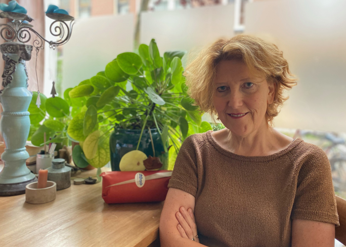 Vrouw met licht rossig haar aan tafel voor een raam met pannekoekenplantjes