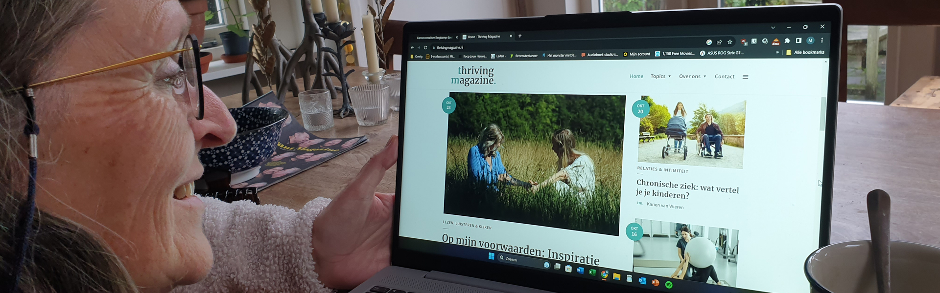 Vrouw aan tafel met laptop met daarop open de website van Thriving Magazine