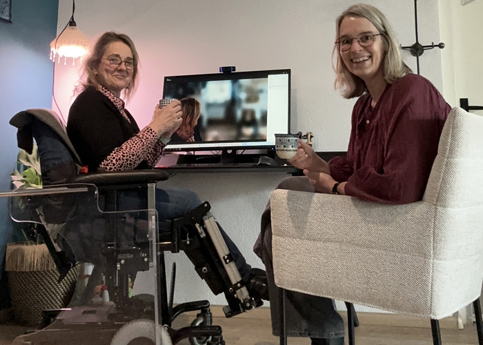 twee vrouwen bezig met begeleiding van online ontmoeting op laptop | rolstoel